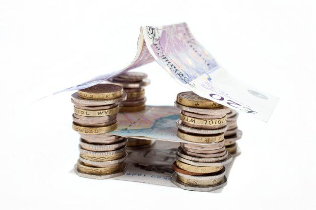 Coins and bank notes built into a house.